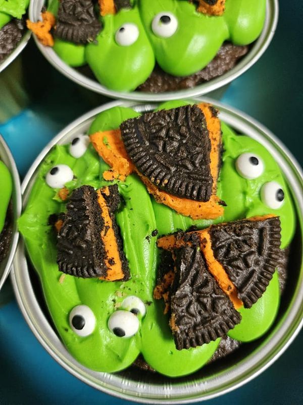 green cupcakes with oreos in the shape of monster heads and eyes on them