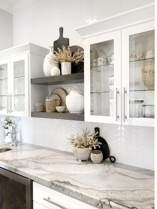 a kitchen with white cabinets and marble counter tops