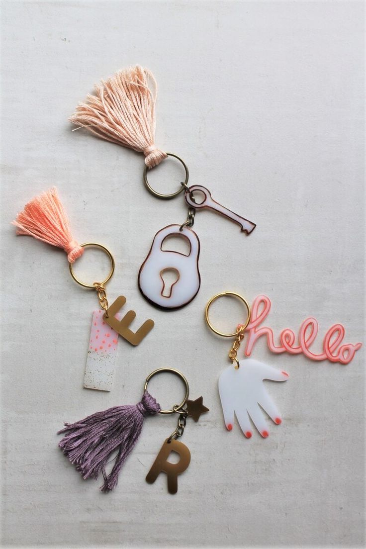 the keychain is decorated with different types of letters and tassels on it