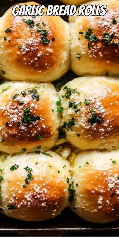 garlic bread rolls in a baking pan with parmesan cheese and herbs on top