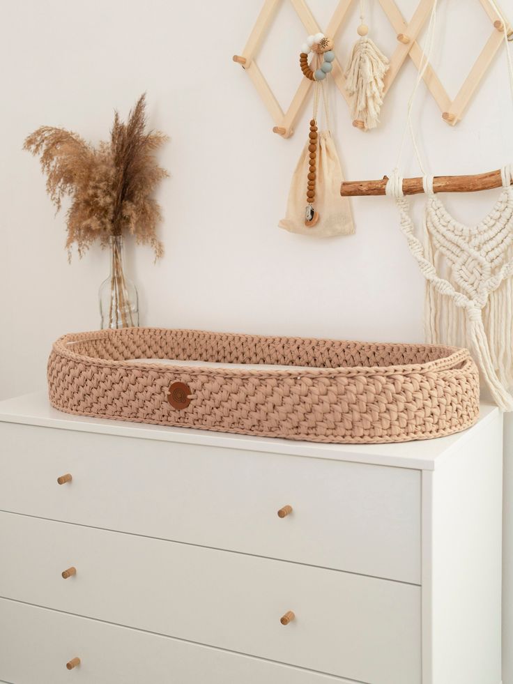 a baby crib in the corner of a room next to a wall with hanging items on it