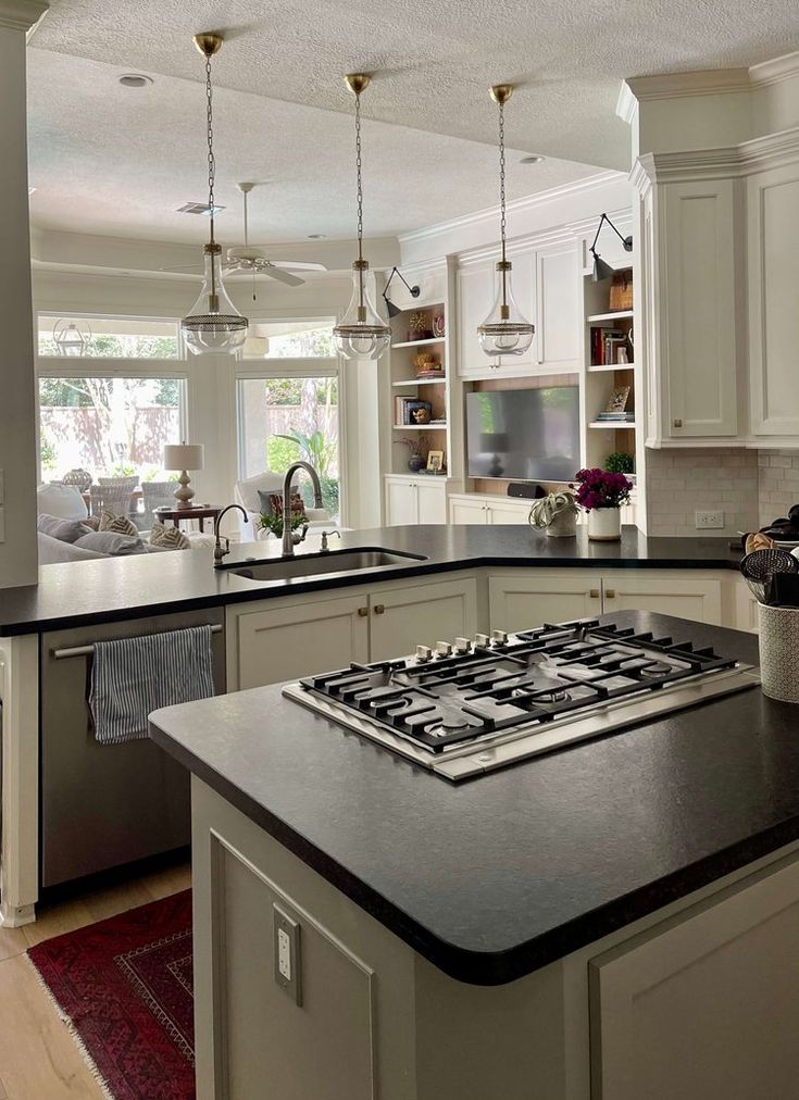 a kitchen with white cabinets and black counter tops, an island in front of the stove