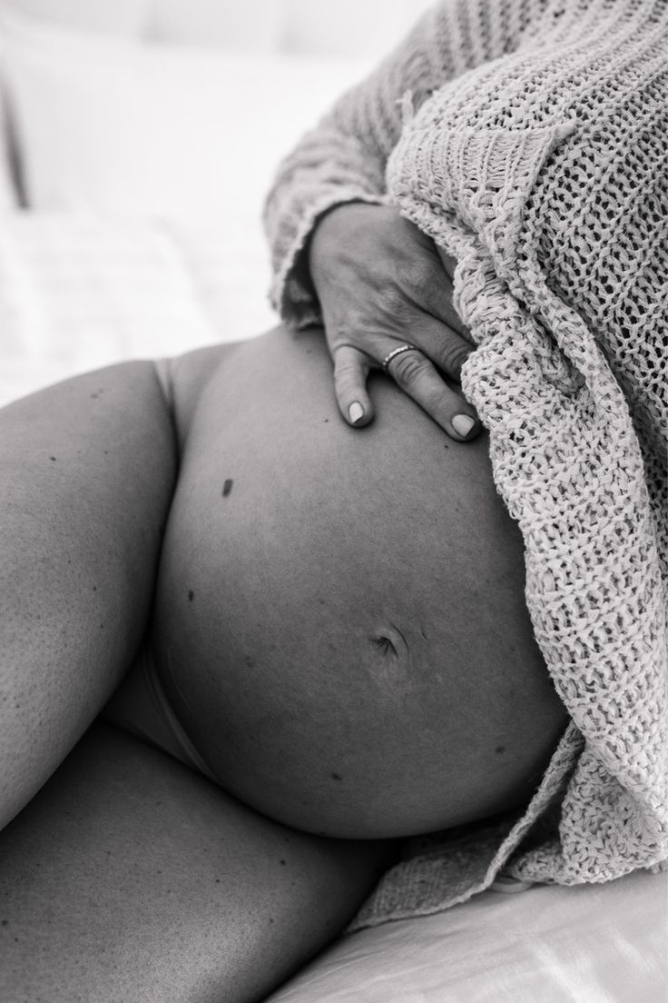 a pregnant woman laying on top of a bed