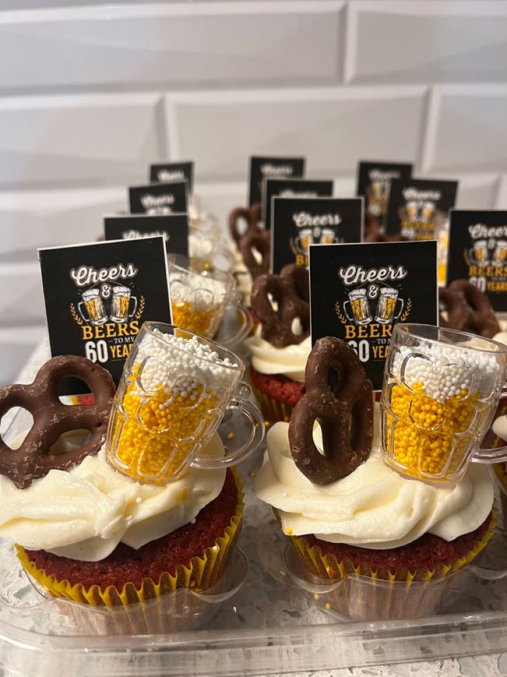 cupcakes with frosting and pretzels on top are decorated with beer glasses