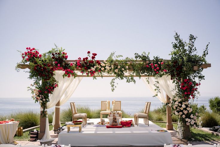 an outdoor table set up for a wedding with flowers on the top and chairs around it