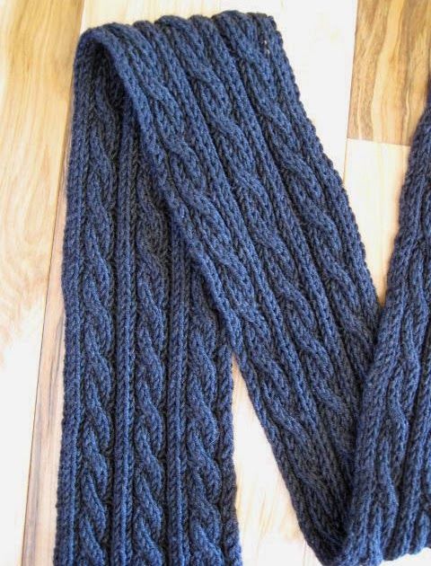 a pair of blue knitted arm warmers on top of a wooden floor,