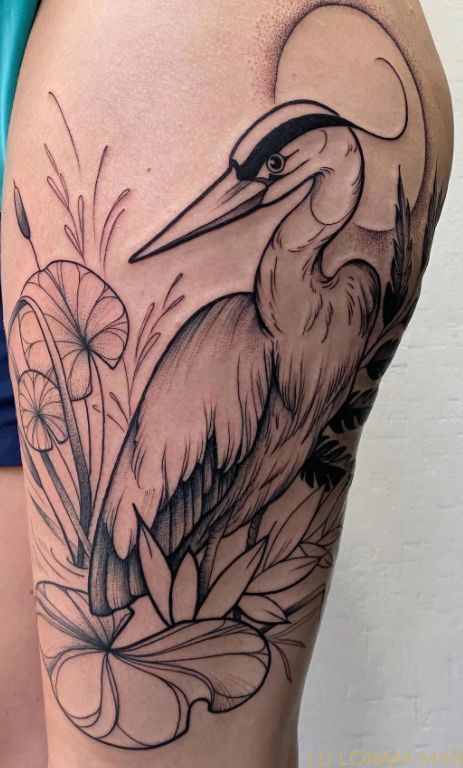 a woman's thigh with a bird and flowers on the side, in black and white