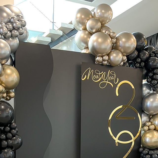 a black and gold birthday sign surrounded by balloons