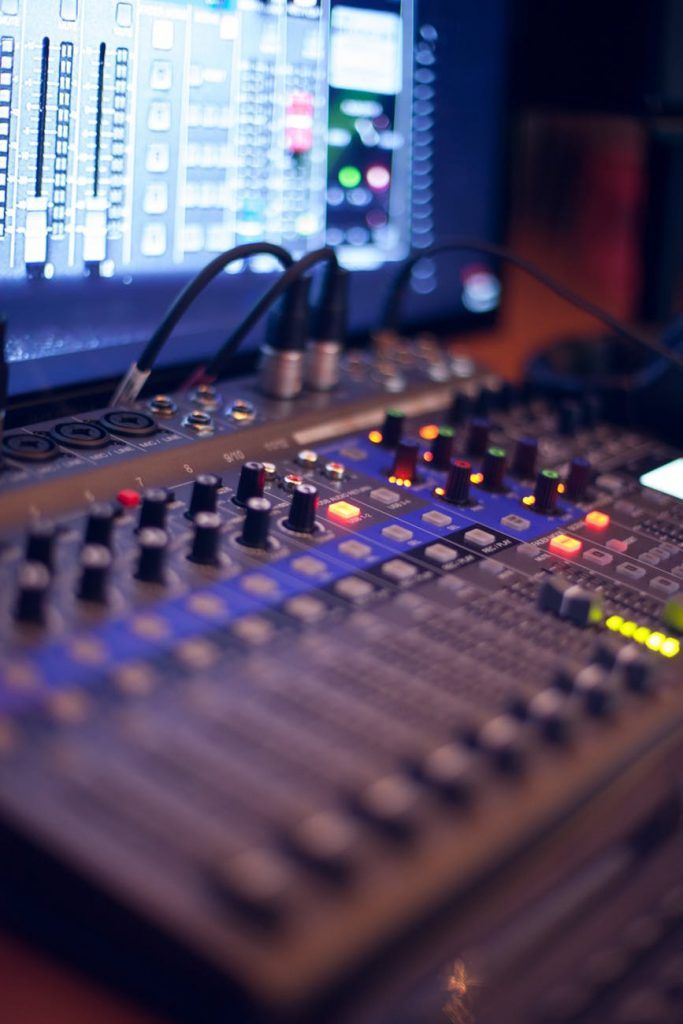 a sound mixing console with multiple knobs in front of a computer screen