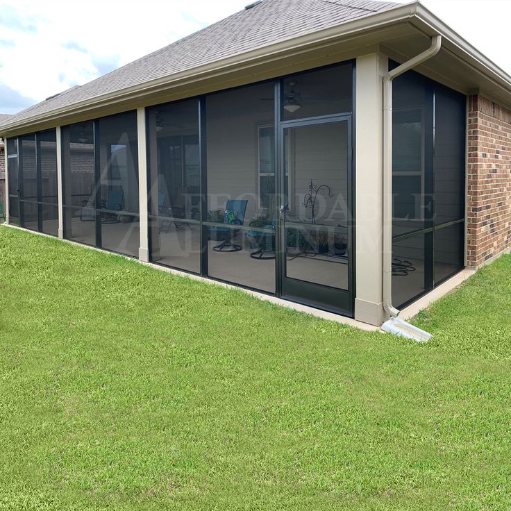 an enclosed patio with sliding glass doors on the side of it and grass in front