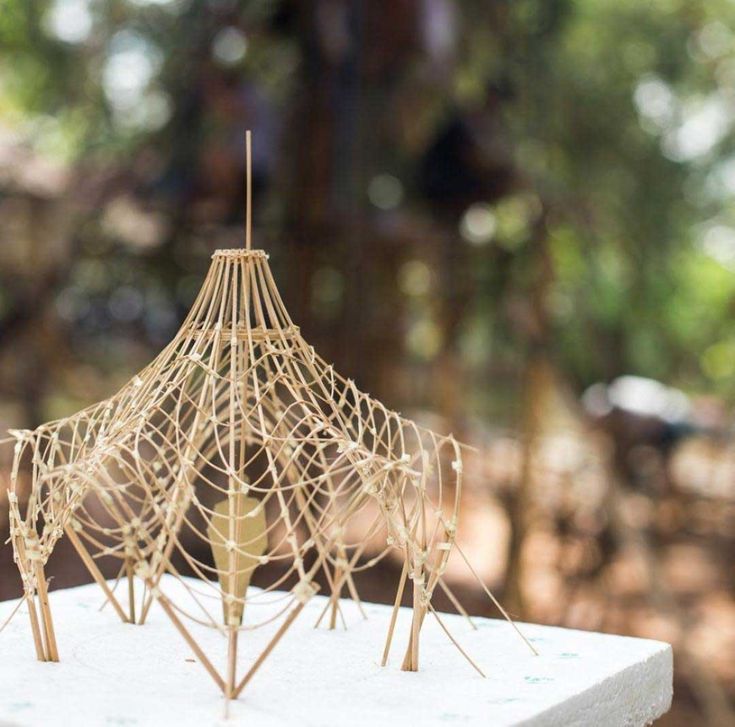 a small wooden structure sitting on top of a white table in front of some trees