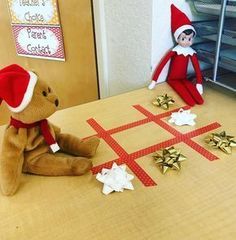 two elfs are sitting at a table with christmas decorations on it and one is playing crossword