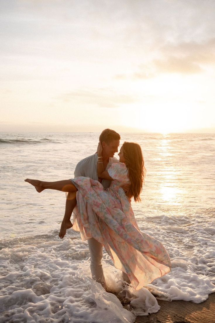 a man holding a woman in his arms on the beach