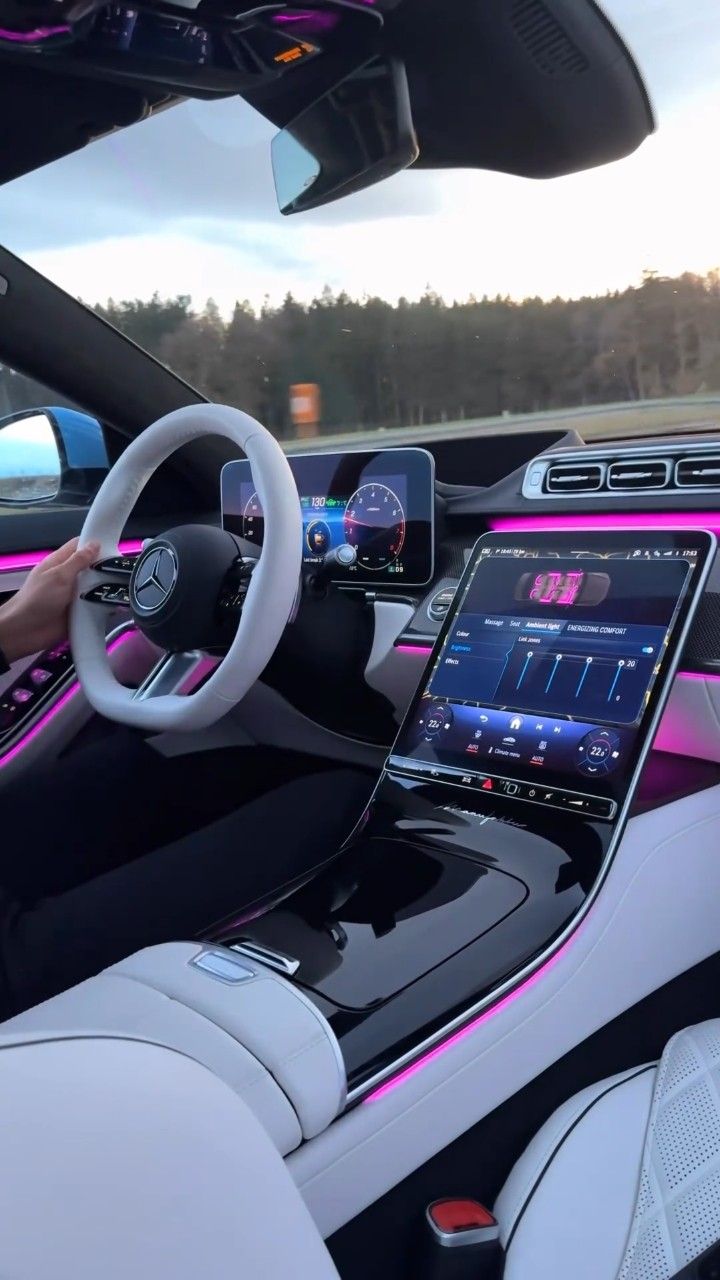 the interior of an electric car with pink lights and dashboard, along with electronic devices