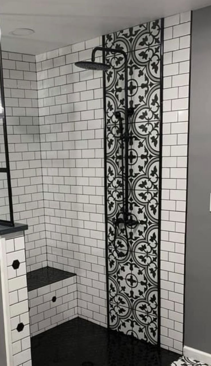 a bathroom with black and white tiles on the walls, flooring and shower stall