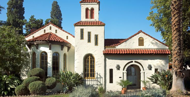 a white church with red tiled roof surrounded by trees