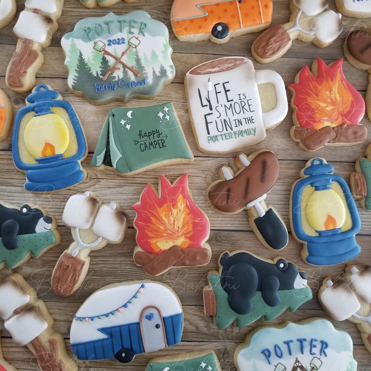 decorated cookies are arranged on a wooden surface with campers, tents and camping signs