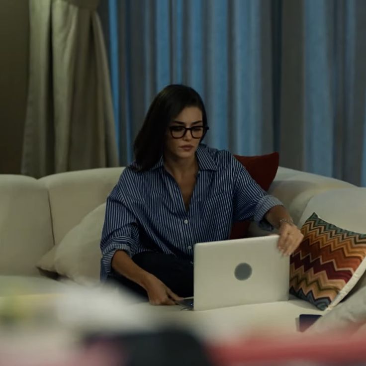 a woman sitting on a couch using a laptop computer