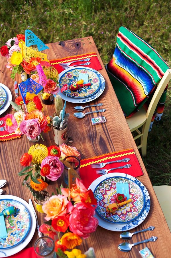 the table is set with colorful flowers and plates