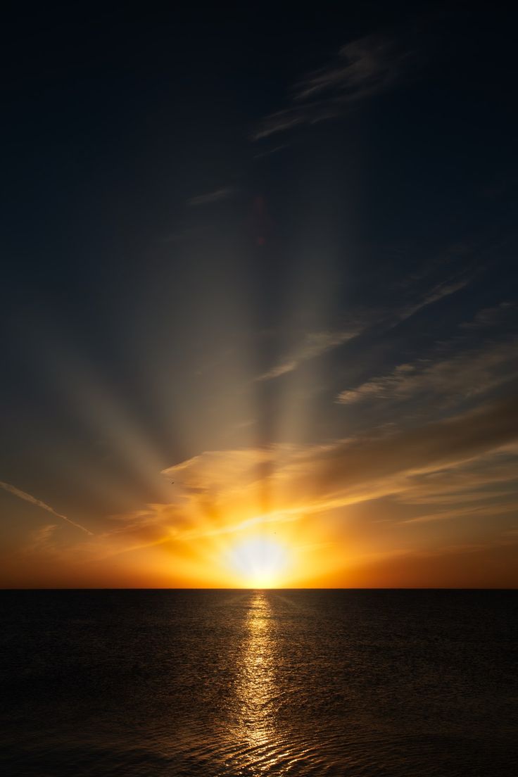 the sun is setting over the ocean with clouds in the sky and water below it