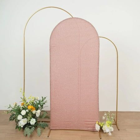 a pink and gold arch with flowers on the floor