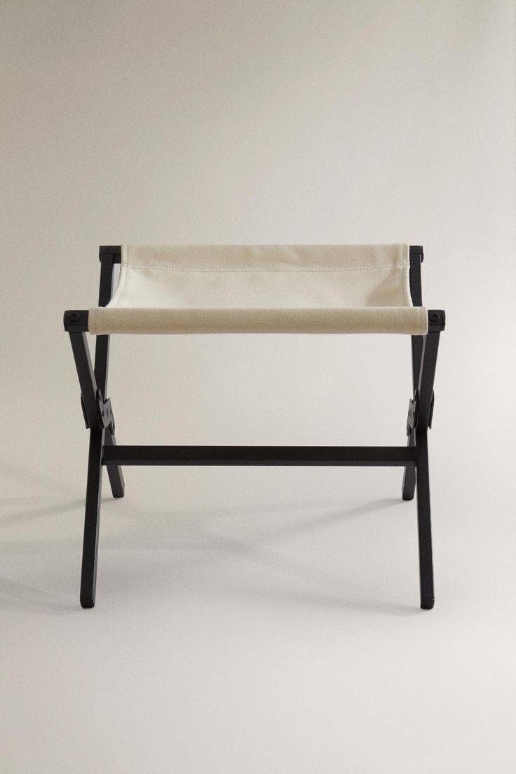 a black and white folding chair with a beige seat cover on it's back