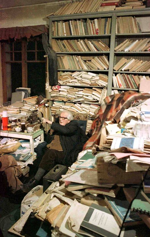 an old man sitting in a room full of books