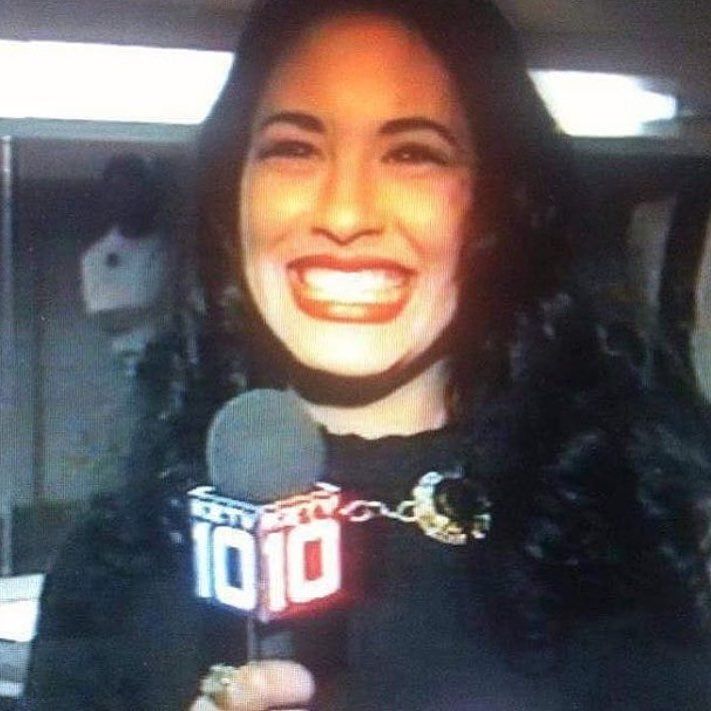 a woman is holding a microphone and smiling at the camera while wearing a black shirt