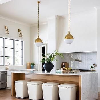 a kitchen with marble counter tops and gold pendant lights hanging from the ceiling over the island