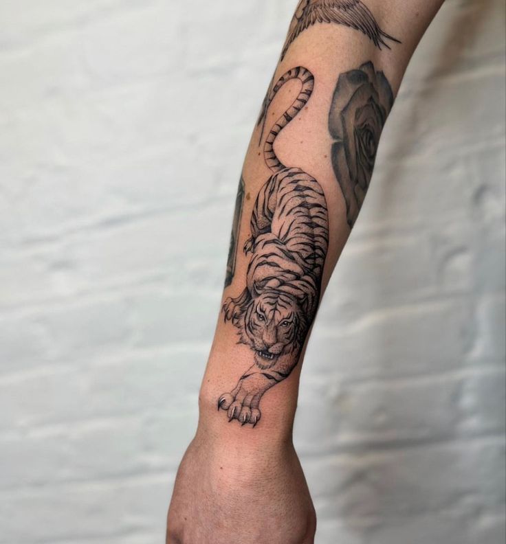 a hand with a tiger tattoo on it's left arm and the other arm