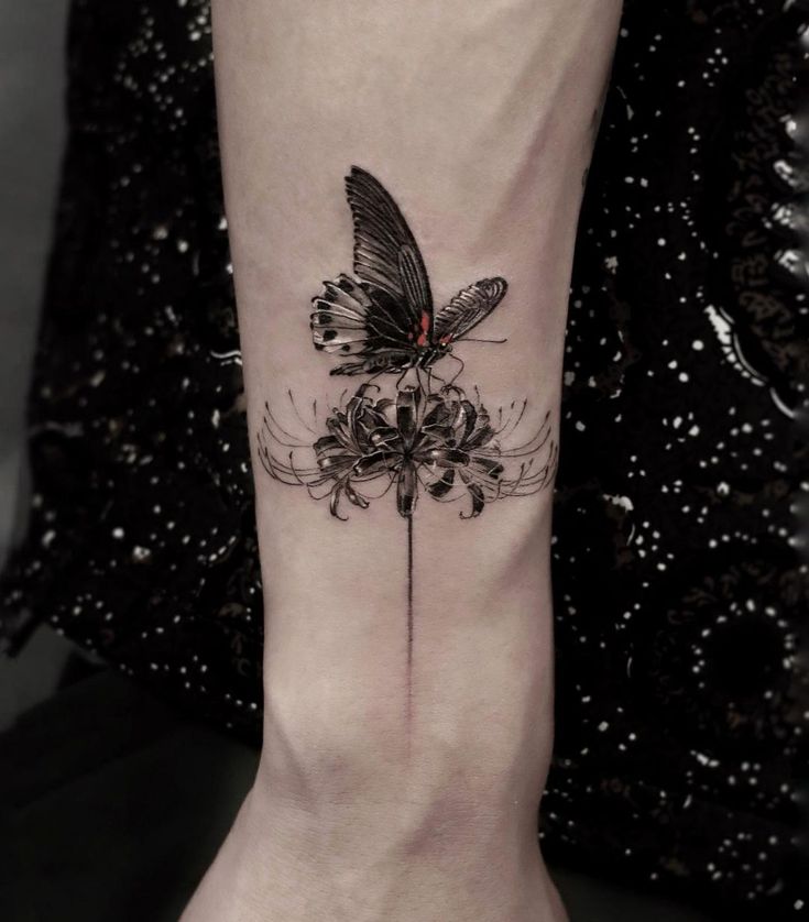 a woman's foot with a butterfly on top of it and flowers in the bottom