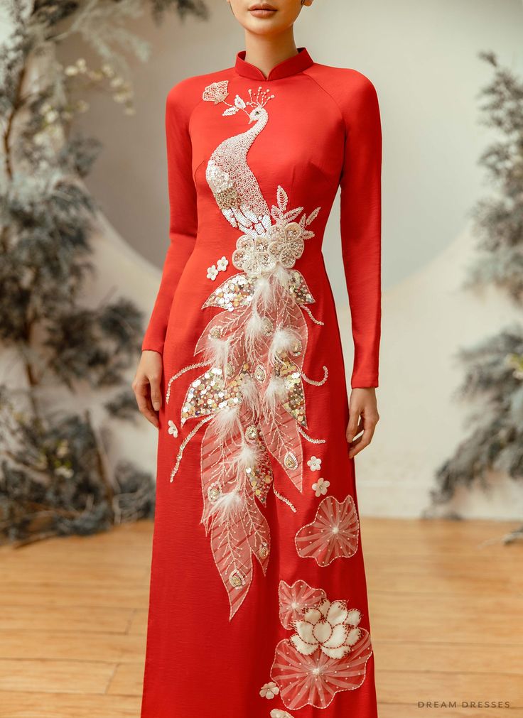 Monalisa is a fabulous alternative to a traditional bridal ao dai gown. This gorgeous dress is embellished with a striking peacock motif design, to signify re-growth, royalty, and honor; ideal for making a statement on your special day! The regal red colorway enhances the ivory beading work, and emphasizes the embroidery shimmer. Monalisa will most certainly make a longlasting impression! Custom made red bridal Ao Dai Peacock motif embellishments Collar: 1.4in/ 3.5cm Long sleeves Zipper closure Bridal Ao Dai, Vietnamese Wedding Dress, Dress With Embellishments, Ao Dai Vietnamese, Vietnamese Wedding, Vietnamese Traditional Dress, Vietnamese Dress, Bridal Dress, Printed Maxi Dress