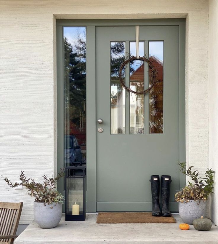 a gray front door with two planters on the steps