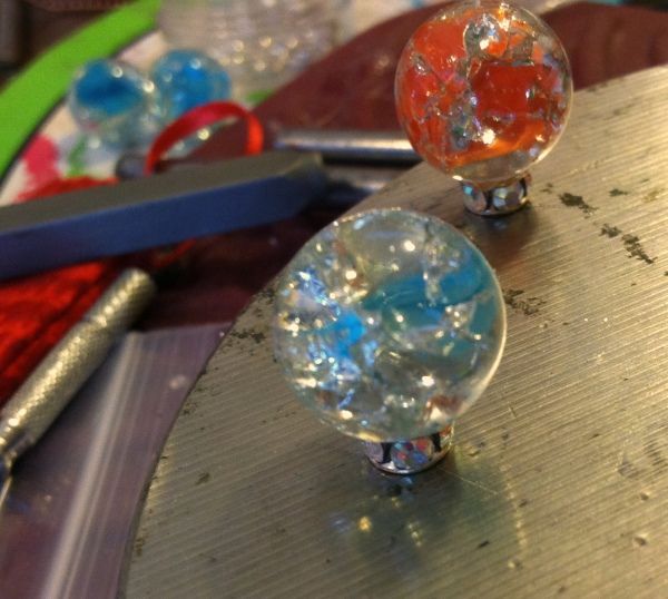 two glass marbles sitting on top of a table next to scissors and other crafting supplies