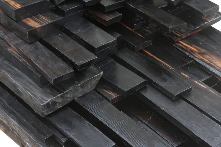 a pile of black wooden planks stacked on top of each other in front of a white background