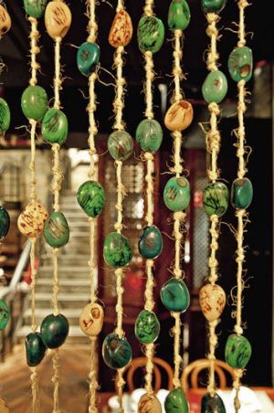 a group of green and gold beads hanging from a rope in front of a table