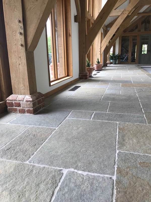 a long hallway with stone flooring and wooden beams