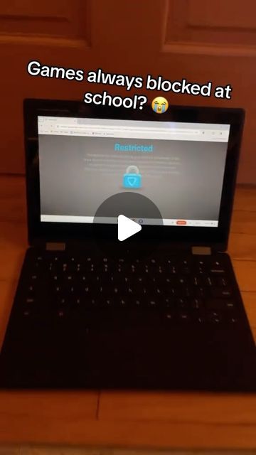 an open laptop computer sitting on top of a wooden floor next to a door with the words games always blocked at school?