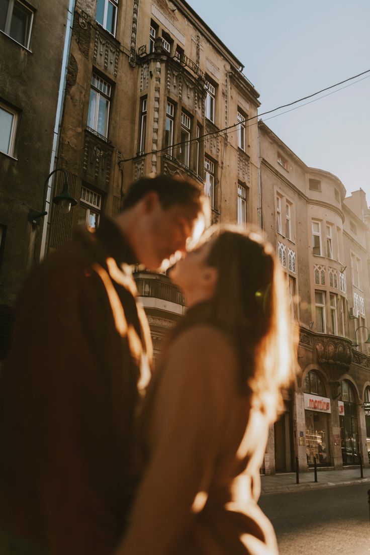 a man and woman are kissing in the middle of an alleyway with buildings behind them