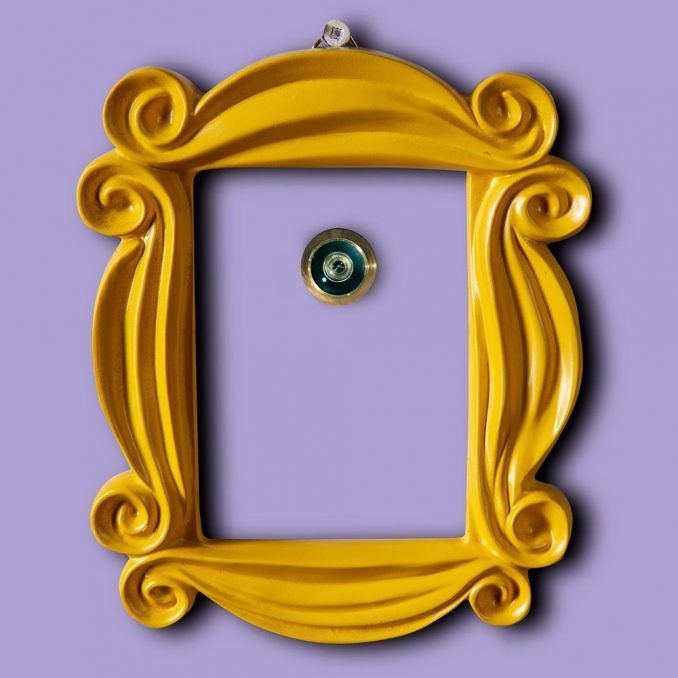 an ornate yellow frame with a green eye in the center on a purple wall background