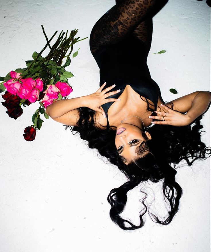 a woman laying on the ground next to flowers and her legs spread out in front of her