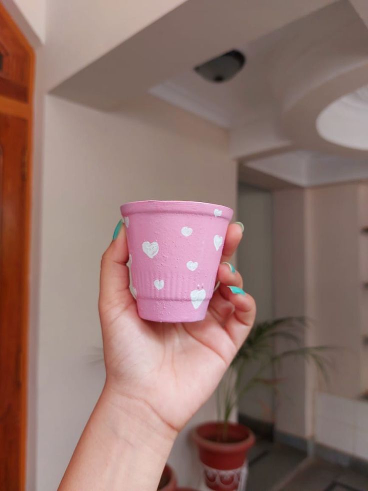 a hand holding a pink cup with hearts on it