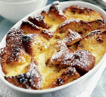 bread pudding in a white dish with powdered sugar on top