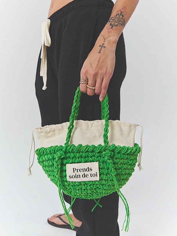 a person holding a green and white crochet bag with the words proud on it