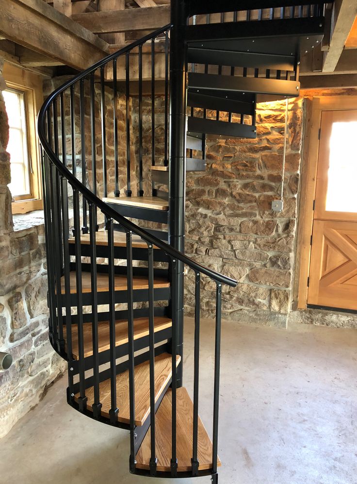 there is a spiral staircase in the middle of a room with stone walls and flooring