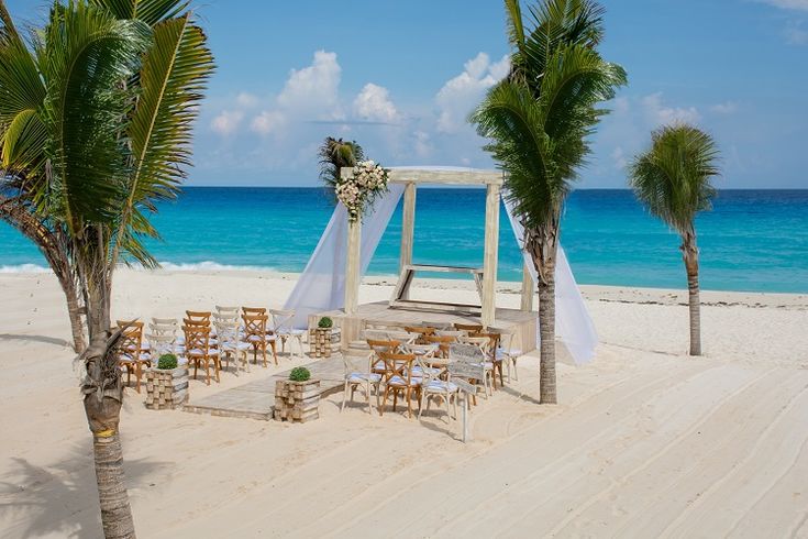 an outdoor wedding setup on the beach with palm trees and blue water in the background