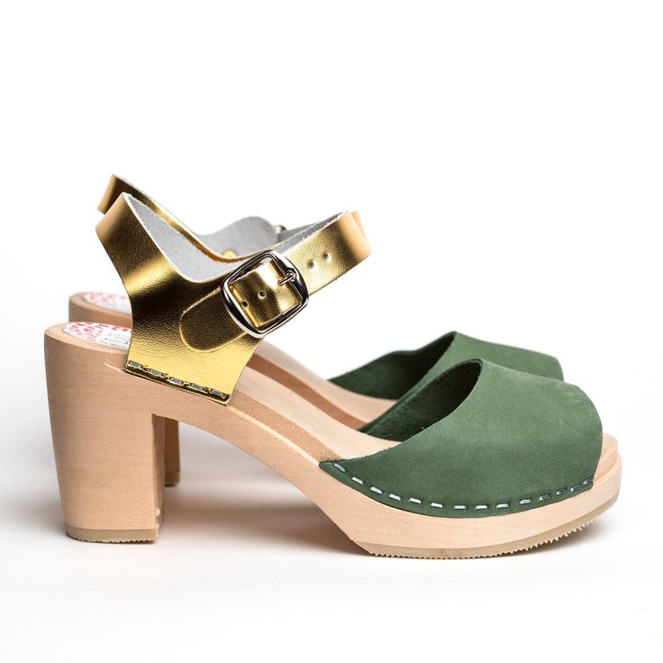 Woman high heeled wooden sandal. Moss green nubuck leather on front part. Gold leather at heel. Wooden sole, 8 cm heels. Handmade in Sweden. The shoe stays true to European sizes. Marks on the wooden sole that might appear with use can easily be removed with a fine sand paper. Do you have questions or need additional information? Please contact us on sofie@liliandlala.com. www.liliandlala.com Lili & Lala was founded by Swedish Alexandra Giertz in India in 2014. Lili & Lala is now Stockho Green Sandals With Sculpted Heel, Green Sandals With Sculpted Open Heel, Green Open Toe Sandals With Sculpted Heel, Green Leather Mules With Padded Heel, Green Sandals With Sculpted Block Heel, Summer Green Mules With Wooden Heel, Green Leather Open Heel Mules, Green Sandals With Heel Strap, Green Open Toe Slingback Sandals With Padded Heel