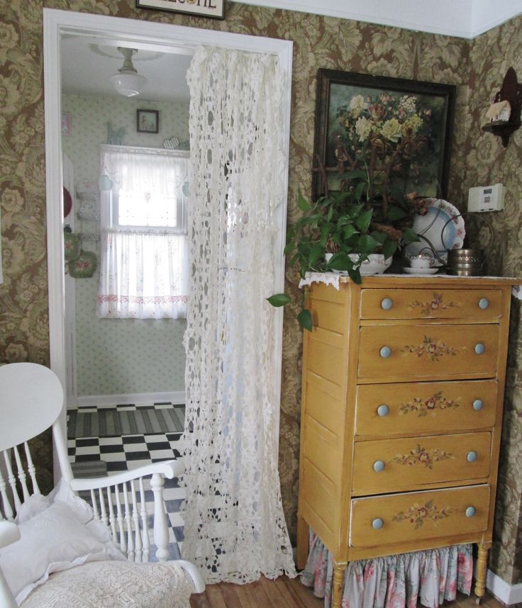 a bedroom with a dresser, bed and mirror in it's corner next to a window