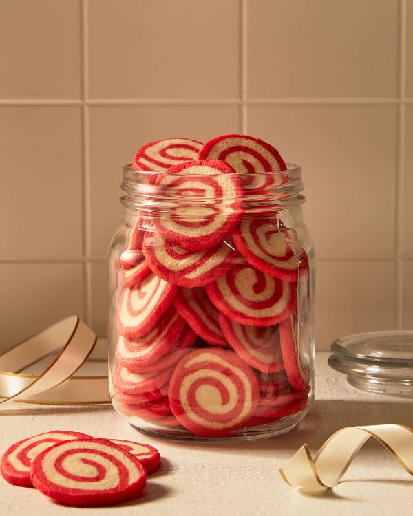 a jar filled with red and white cookies on top of a counter