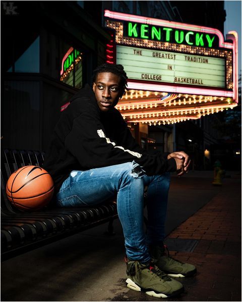 a young man sitting on a bench with a basketball in his hand and the marquee behind him